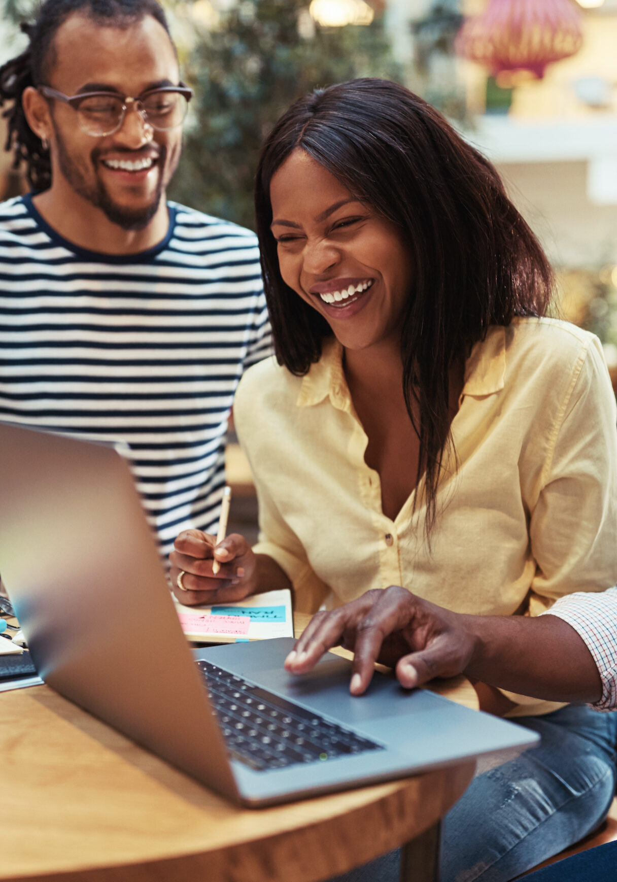 Laughing businesspeople sitting in an office lounge using a laptop